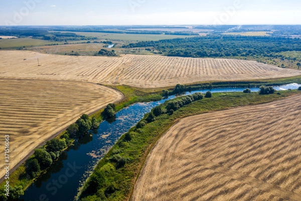 Fototapeta aerial photography of a bend in a river flowing through mown fields