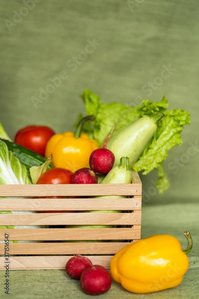 Obraz Fruits and veggies in wood box with green background.