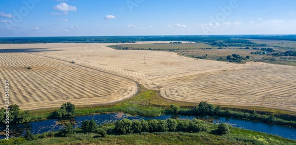 Obraz aerial photography of a bend in a river flowing through mown fields