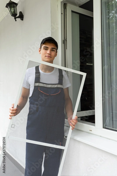 Obraz Construction worker sets mosquito net on a plastic windows