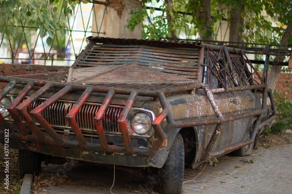 Fototapeta Close-up of a brutal grunge rusty car near a bar in the city of Yarovoe (Altai Territory).