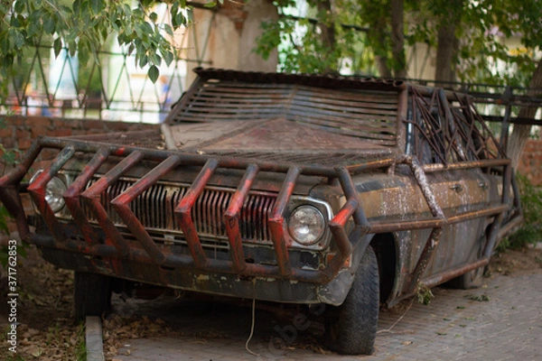Fototapeta Close-up of a brutal grunge rusty car near a bar in the city of Yarovoe (Altai Territory).