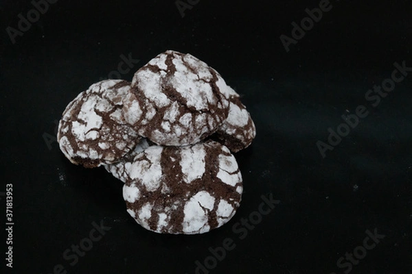 Obraz Homemade cookies with chocolate chips with powdered sugar on black background. Freshly baked choco cookie close up. Dark food. Cook at home.
