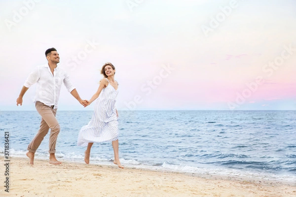 Fototapeta Happy couple having romantic walk on beach. Space for text
