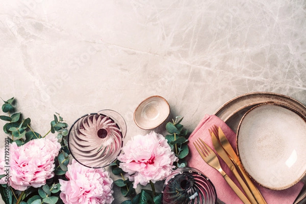 Obraz Flower arrangement on table served for festive dinner with copy space for your text, invitation. Greeting card. Top view. Peony, eucalyptus, plates, golden cutlery, wineglasses on marble background
