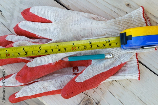 Fototapeta Work gloves, measuring tape and pencil. View from above.