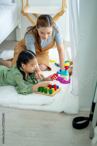 Fototapeta Happy asian family moher and daughter and playing with toy blocks at home. Home activities for family.