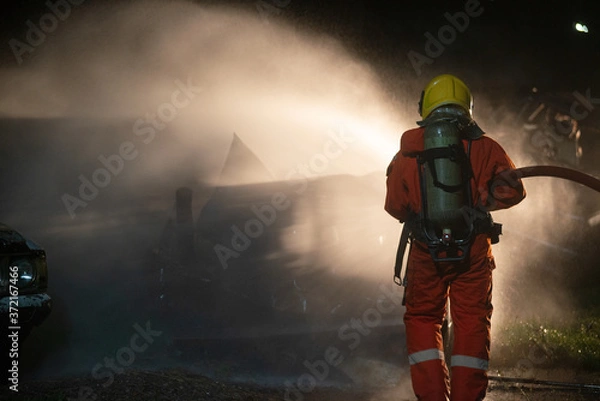 Fototapeta Firefighters spraying water to put out a brutal fire on the car.