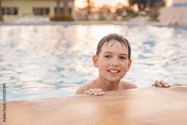 Fototapeta a boy of European appearance 7 years old swims in the pool at sunset