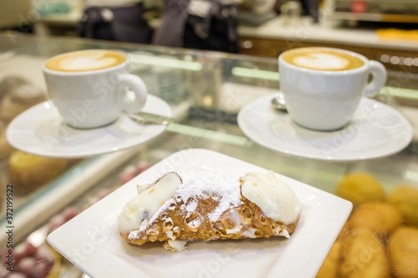 Fototapeta Two cups of cappuccino and fresh ricotta cannoli dessert close-up in coffee bar in Sicily, Italy.