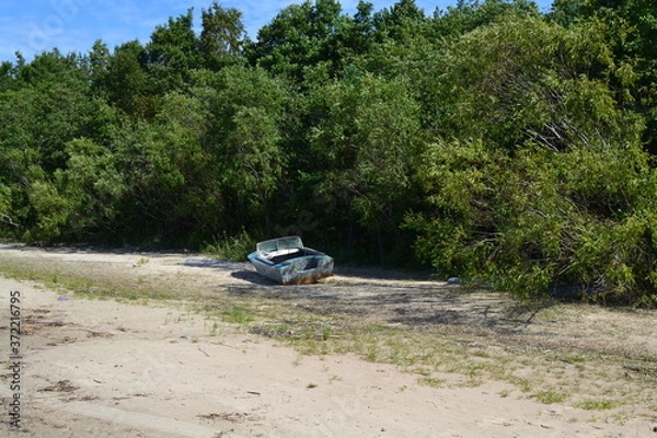 Obraz an old boat on the sandy shore of the lake on a summer day