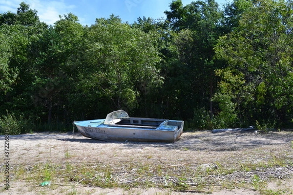 Obraz an old boat on the sandy shore of the lake on a summer day