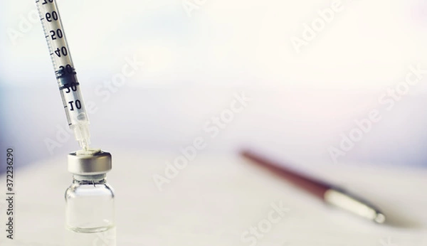 Obraz A man signs a medical document. Medical equipment on the table. Stethoscope and ampoules with syringes. Makes notes in the office. Medical center.