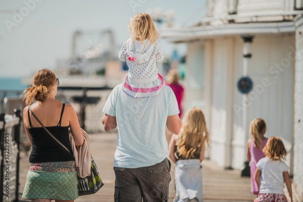 Fototapeta Family of 6 enjoy a day out at Brighton Beach Pier during the Covid-19 pandemic 