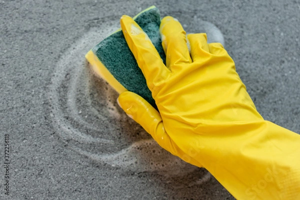 Obraz Woman's hands in yellow gloves cleaning counter top in kitchen