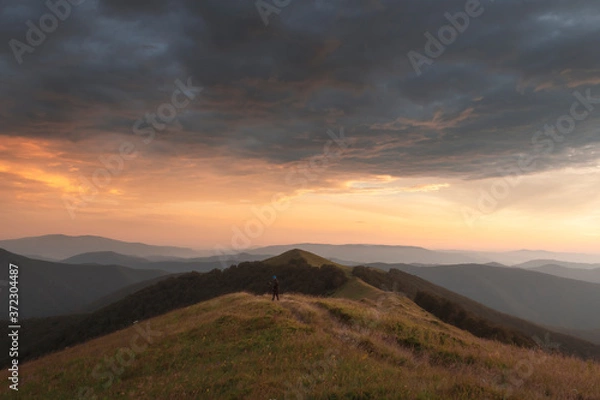 Obraz Fotograf robi zdjęcie jesiennego krajobrazu z mglistymi szczytami i drzewami pomarańczowymi. Ukraińskie Karpaty