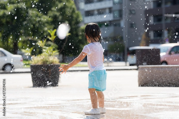 Fototapeta 広場の噴水で水遊びする子供