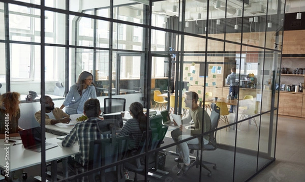 Fototapeta Business meeting. Group of happy smiling multiracial business people discussing project, working together while sitting in a conference room in the modern coworking space