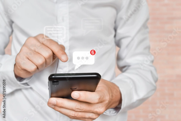 Fototapeta Businessman hand using mobile phone typing, with chat icons. Social media and technology concept.