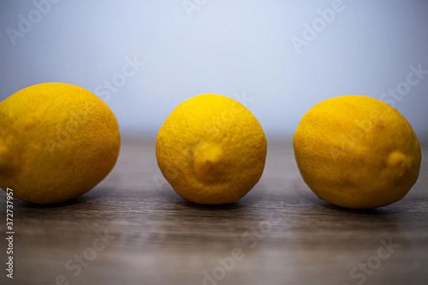 Obraz Three large whole lemons lie on a wooden table