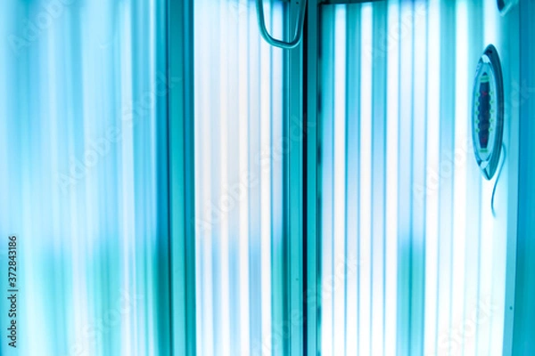 Obraz Vertical Tanning turbo Solarium Light Machine with glowing blue light ultraviolet lamps for tanning and skin care. Empty tanning Modern solarium, inside. Horizontal photo