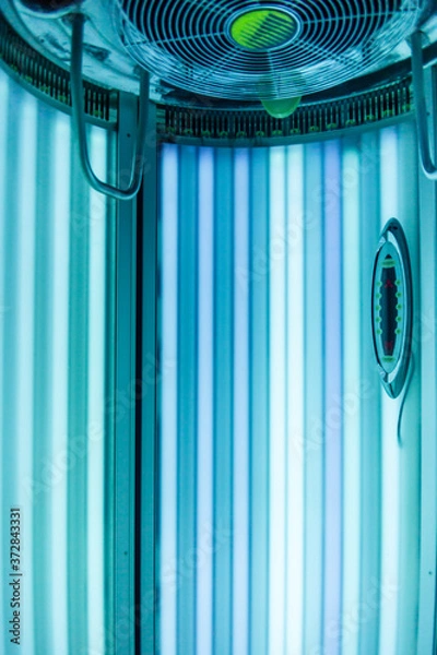 Obraz Vertical Tanning turbo Solarium Light Machine with glowing blue light ultraviolet lamps for tanning and skin care. Empty tanning Modern solarium, inside. Horizontal photo