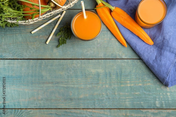 Fototapeta Freshly made carrot juice on wooden table, flat lay. Space for text