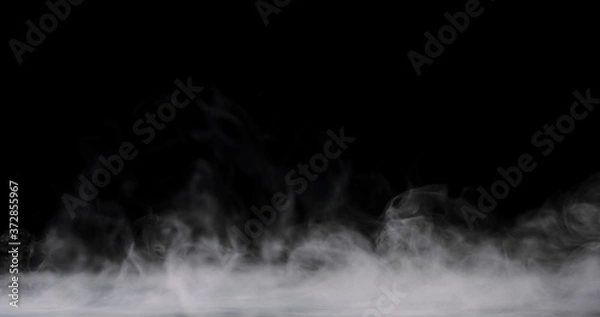 Fototapeta white fog rolling across the ground against a black background and staying low.