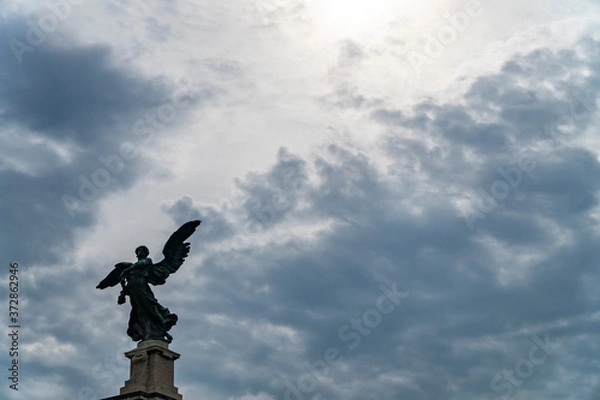 Fototapeta Statue of an angel in Rome and clouds background with sun rays as divine light