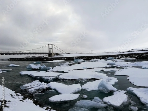 Fototapeta  glacier lagoon in iceland with a suspension bridge in the background, chunks of ice
