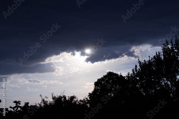 Fototapeta The sun runs away from thunderclouds.