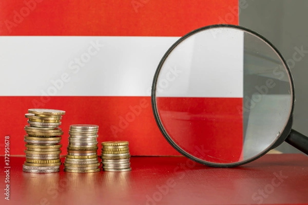 Fototapeta Magnifying glass and coins in front of Austria flag, country economy concept