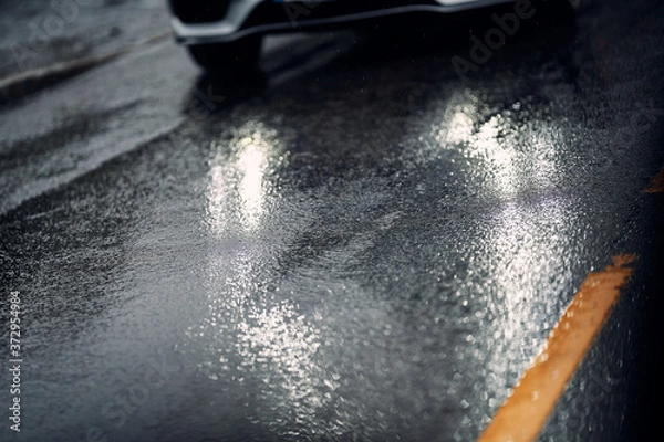 Fototapeta Car on wet and slippery asfalt. Close up on tires and the road. Rain and wet driving conditions. 