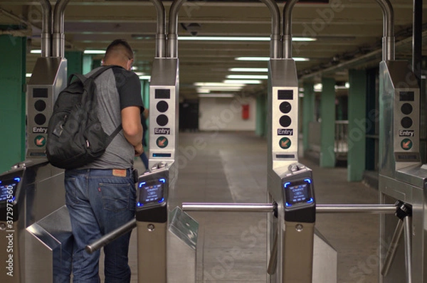 Fototapeta New York City MTA Subway Station Person Walking Through Turnstile with Metrocard