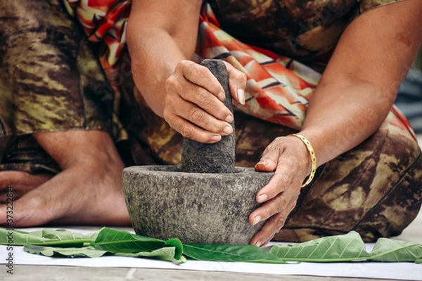 Obraz Closeup shot of hands of an Indian female grinding leaves to make paste using Mortar and Pestle.