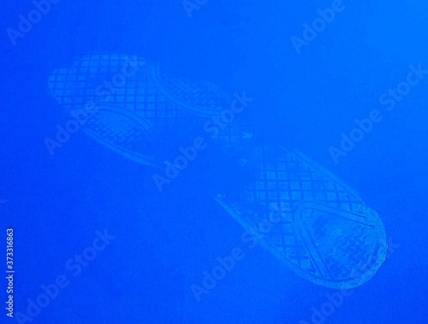 Fototapeta White footprint from a boot smeared with whitewash on a blue background close-up.