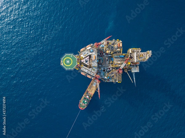 Fototapeta Aerial view from a drone of an offshore jack up rig at the offshore location with a supply boat
