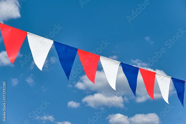 Fototapeta Red white and blue triangular bunting on sky background
