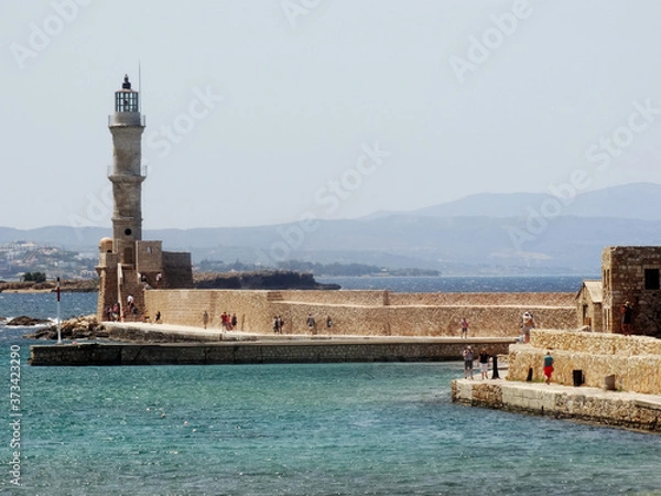 Fototapeta Tourists visit the lighthouse in Chania central in Crete, Greece. The original Venetian lighthouse was built around the late 16th century to protect the harbour.