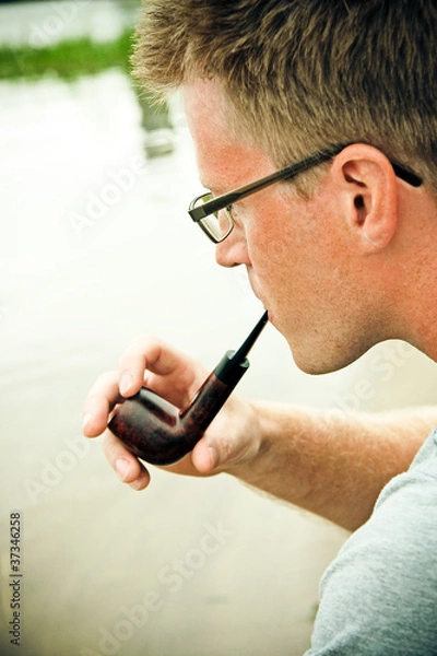 Obraz man smoking a pipe, river on background