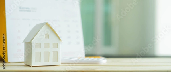 Fototapeta close up on home model with calculator and calendar on blue  background with space for money management ,home loan and personal financial concept