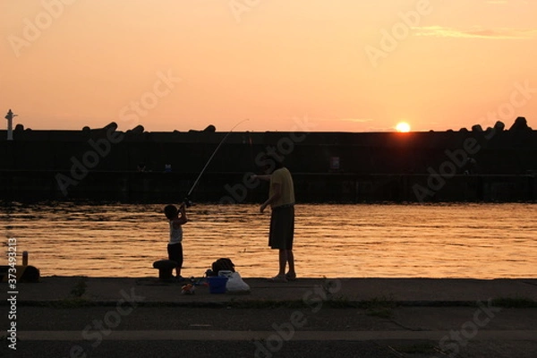 Obraz 夕暮れの港で堤防釣りをする子供と母親