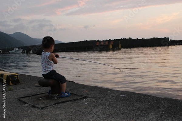 Obraz 夕暮れの港で堤防釣りをする男の子（幼児）