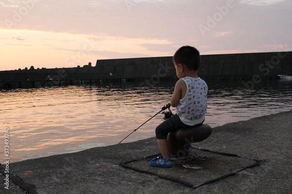 Obraz 夕暮れの港で堤防釣りをする男の子（幼児）
