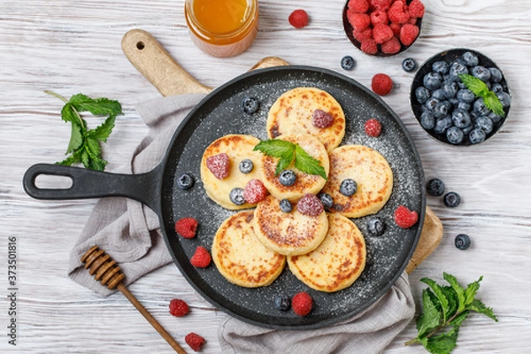 Obraz Cottage cheese pancakes with raspberry and blueberry in pan on rustic background, breakfast or lunch