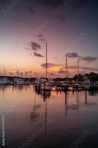 Fototapeta Predawn at the marina with sailboats at the dock in calm water.