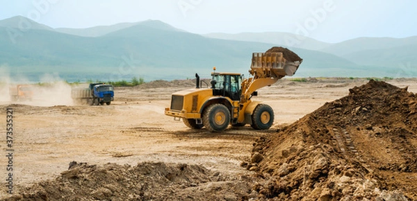 Fototapeta Loading earth soil into the side of a cargo dump truck with a front loader bucket