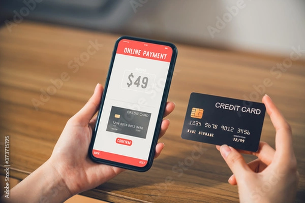 Fototapeta Hand holding smartphone and using application shopping online with payment by credit card online.