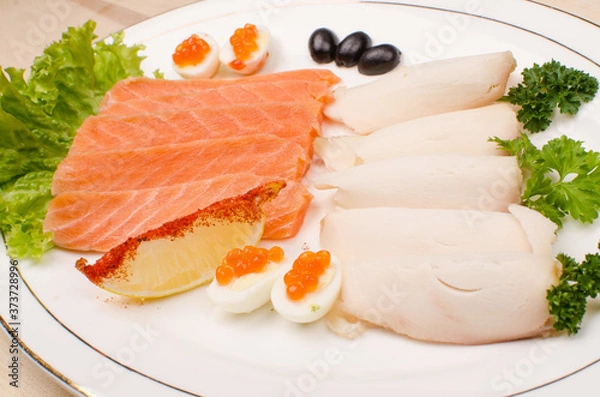 Fototapeta on a white plate is a salmon fillet sliced and chicken fillet surrounded by greens with lemon