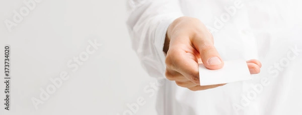 Fototapeta  girl in a white office shirt holds out a business card. close portrait.